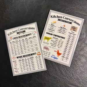 K&ouml;nnte beinhalten: Zwei wei&szlig;e magnetische K&uuml;chenumrechnungstabellen mit schwarzem Text und bunten Illustrationen. Die linke Tabelle zeigt Fl&uuml;ssigkeits- und Gewichtsma&szlig;e in US-amerikanischen Einheiten. Die rechte Tabelle zeigt die Garzeiten f&uuml;r Eier, die Ofentemperaturen in Fahrenheit und Celsius sowie die Gartemperaturen f&uuml;r Rindfleisch, Schweinefleisch, Gefl&uuml;gel und Fisch.