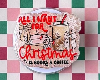 May include: A clear tablet case featuring a pink, dark red, and green checkered pattern. Attached to the center is a glittery, circular phone grip with an illustration of books, a coffee cup, and the text All I Want For Christmas Is Books & Coffee.