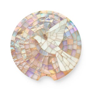 May include: Round car coaster with a mosaic design featuring a white dove in flight. The coaster has a pearlescent finish with shades of pink, purple, and gold. The dove is made of white tiles.
