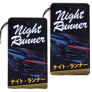 May include: Two black car air fresheners with a blue car graphic and the text "Night Runner" in white. The text "ナイトランナー" is printed in yellow on the bottom of each air freshener.