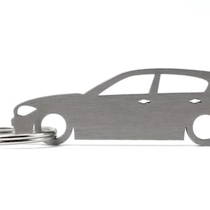 Puede incluir: Un llavero de metal plateado con forma de coche. El llavero tiene un anillo.
