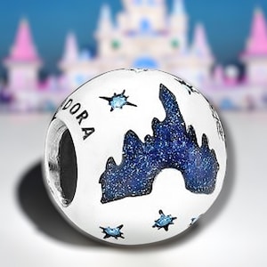 Könnte beinhalten: Weißer Anhänger mit einer blauen Silhouette von Schloss Aschenputtel mit blauem Glitzer und Sternen. Der Anhänger trägt die Aufschrift "Pandora" an der Seite.