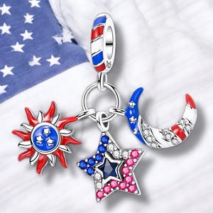 Könnte beinhalten: Ein silbernes Charm-Armband mit drei Charms: einer rot-weiß-blauen Sonne, einem rot-weiß-blauen Stern und einem rot-weiß-blauen Halbmond. Die Charms sind mit weißen Kristallen verziert.