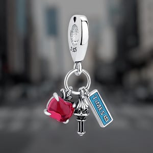 Könnte beinhalten: Silberner Anhänger mit einem roten Herzen, einer silbernen Nachbildung des Times Square Turms und einem blauen Schild mit der Aufschrift "TIMES SQ".