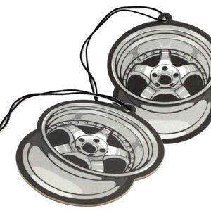 Puede incluir: Dos ambientadores de coche en forma de llanta de coche, en blanco y negro, con una cuerda para colgar.