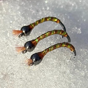 May include: Three brown and gold fly fishing lures with black beads and orange feathers.