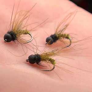May include: Three black and green fly fishing lures with brown feathers.