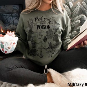 May include: Military green sweatshirt with a black graphic of various mushrooms and the text "Pick your POISON". The sweatshirt is made of a soft material.