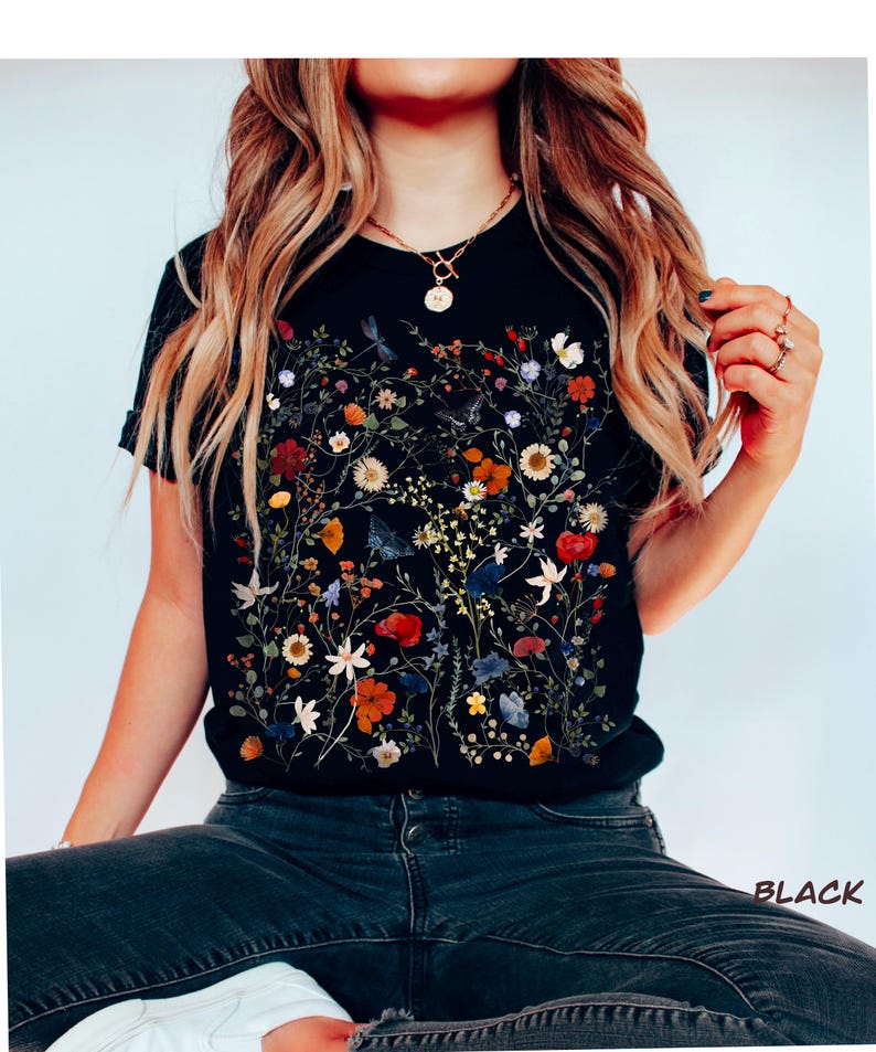 May include: Black t-shirt with a floral print featuring pressed flowers in various colors, including red, orange, yellow, blue, and white.