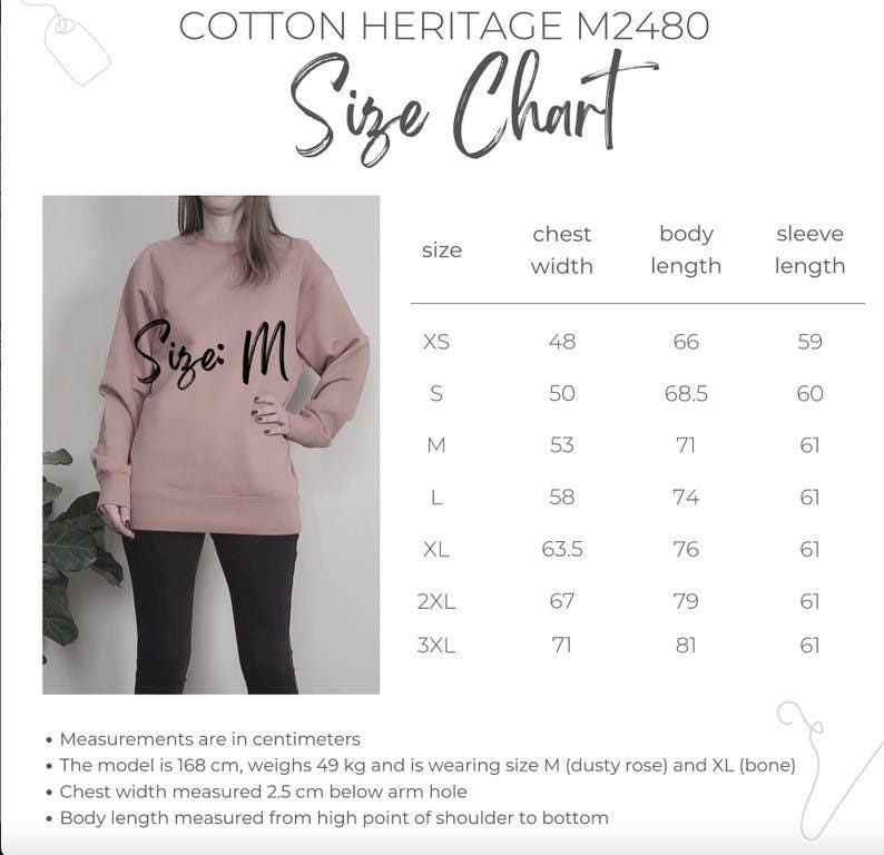 May include: A Cotton Heritage M2480 size chart featuring a dusty rose sweatshirt in size M. The chart lists chest width, body length, and sleeve length in centimeters for sizes XS through 3XL. Text includes model details and measurement instructions.