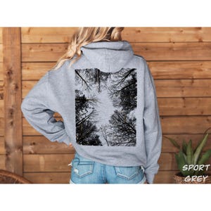 K&ouml;nnte beinhalten: Hellgrauer Kapuzenpullover mit einem schwarz-wei&szlig;en Baumkronen-Design auf dem R&uuml;cken. Der Kapuzenpullover hat eine Kapuze mit Kordelzug und lange &Auml;rmel. Der Text "SPORT GREY" ist in Wei&szlig; unten rechts aufgedruckt.