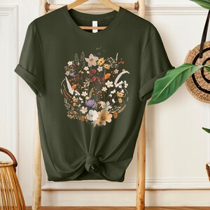 May include: A dark green t-shirt with a floral print featuring a variety of flowers in shades of white, yellow, orange, and purple.