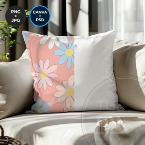 Puede incluir: Una almohada rosa con un patrón de margaritas blancas en un lado y un lado blanco liso en el otro. La almohada está sentada en un sofá marrón claro.