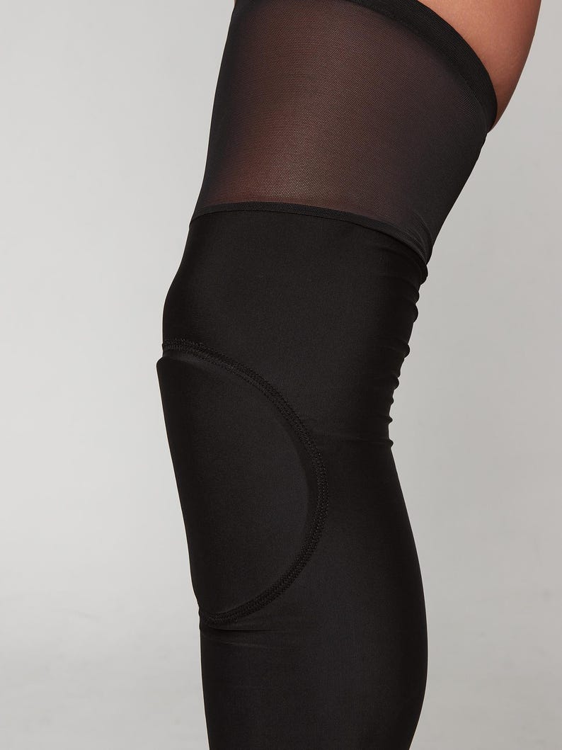 K&ouml;nnte beinhalten: Schwarze Leggings, die bis zum Knie reichen, mit einem Mesh-Einsatz und einem gepolsterten Knieschutz.