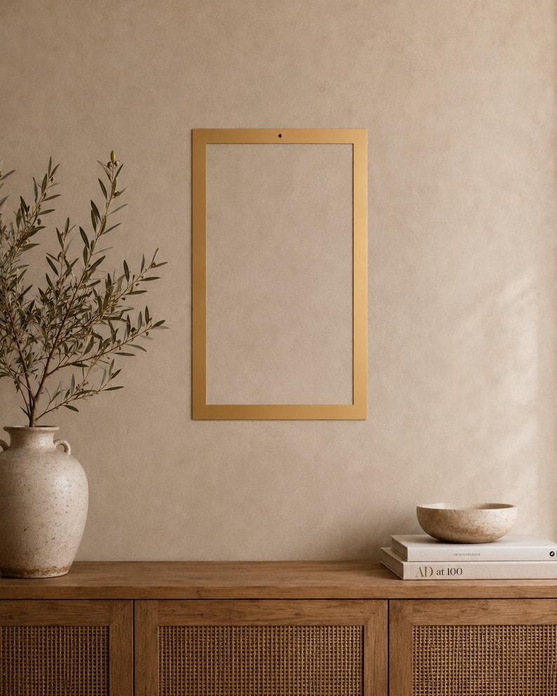 Op de afbeelding: Een rechthoekig goudkleurig metalen frame met een enkel klein gaatje in het midden bovenaan voor montage. Het frame is leeg, heeft een strak, vlak oppervlak en een uniforme metalen afwerking, ontworpen voor wandmontage van prints.