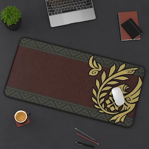 Op de afbeelding: Een bruine en groene muismat met een gouden ontwerp van een gestileerde vogel en bladeren. Het ontwerp bevindt zich aan de rechterkant van de muismat, de linkerkant is effen bruin met een groene rand.
