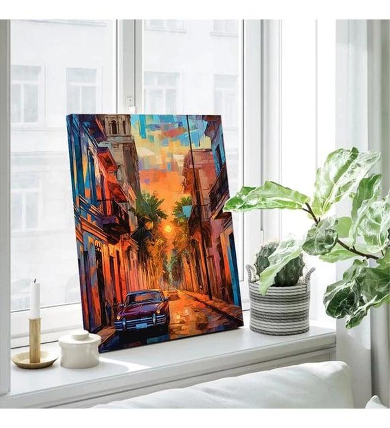 a painting on a window sill next to a potted plant