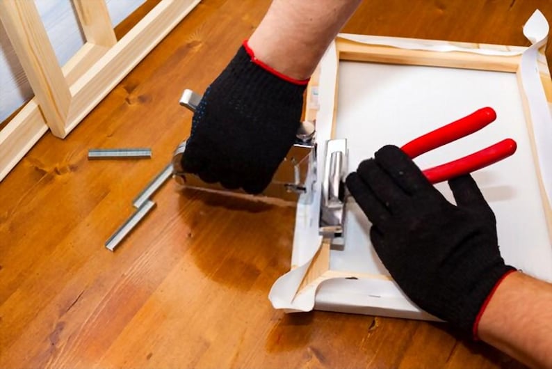 a person in black gloves and black gloves holding a pair of red scissors
