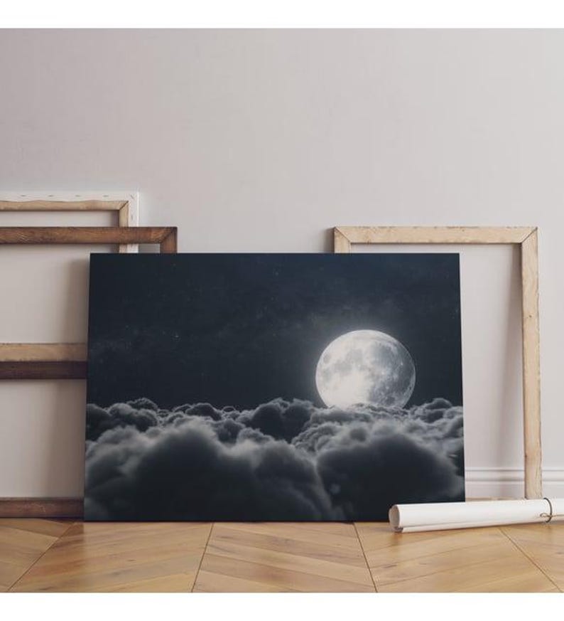a black and white photo of a full moon above the clouds
