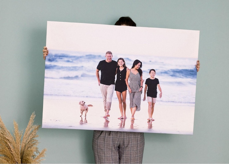 a man holding up a picture of a family on the beach