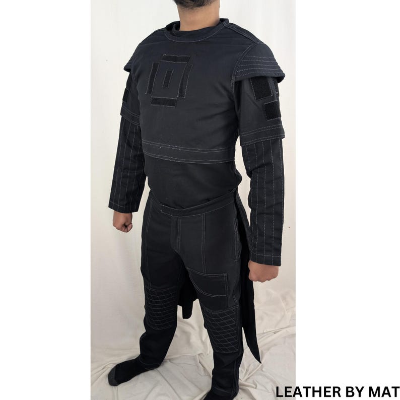 K&ouml;nnte beinhalten: Schwarz-wei&szlig;es Kost&uuml;m mit geometrischem Design auf der Brust und gesteppten Details an Hose und &Auml;rmeln. LEATHER BY MAT steht in wei&szlig;er Schrift auf schwarzem Hintergrund in der unteren rechten Ecke des Bildes.