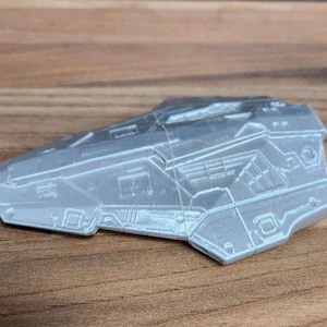 May include: A grey, detailed, spaceship model with a sharp, angular design. The model is made of plastic and has a smooth, matte finish.