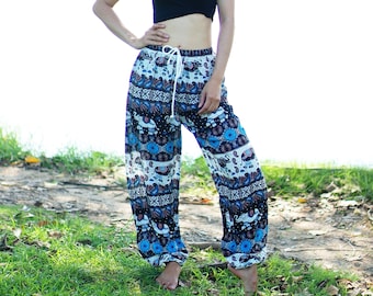 May include: A woman wearing a black tank top and blue and white patterned pants with an elephant print. The pants have a drawstring waist and are loose fitting.