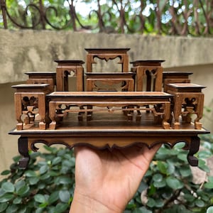 May include: A collection of small, intricately carved wooden display stands in varying sizes and shapes. The stands are a warm brown color, with detailed cut-out designs and decorative edges. The arrangement suggests a display or presentation set.