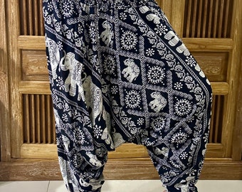Puede incluir: Pantalones de harén negros con estampado de elefante blanco. Los pantalones tienen una cintura elástica y un cordón.