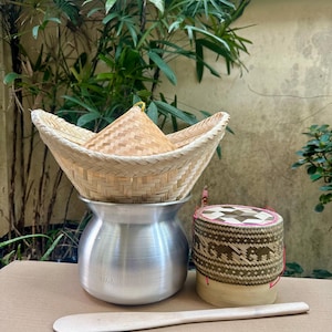 Peut inclure: Un ensemble de trois récipients en bambou tissé pour cuire du riz gluant. L'ensemble comprend un récipient rond avec un couvercle, un récipient rond plus petit avec un couvercle et une spatule en bois.