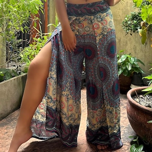 May include: Wide-leg pants with a split design. The pants feature a beige background with a repeating pattern of teal, red, and navy blue circular designs. The waistband is navy blue with a paisley pattern.