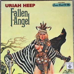 Può includere: Copertina dell'album "Fallen Angel" degli Uriah Heep. L'artwork presenta una donna in abiti fantasy con un uccello nero, una spada e il testo "Fallen Angel". Il titolo dell'album è in un font stilizzato, con il nome della band sopra.