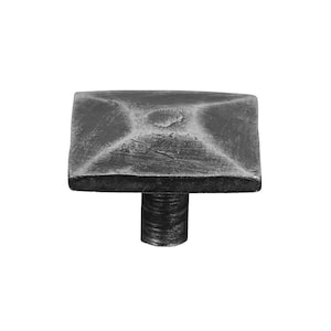 Könnte beinhalten: Ein quadratischer Schrank-Knopf mit einer strukturierten Oberfläche und einer silbernen Oberfläche. Der Knopf hat einen kurzen, zylindrischen Stiel.