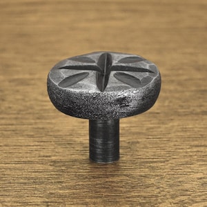 Könnte beinhalten: Ein silberner Metall-Schrankknauf mit sternförmigem Design. Der Knauf hat eine runde Basis und einen zylindrischen Stiel.