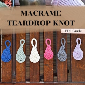 May include: Six macrame teardrop knots in different colors: blue, green, white, pink, gray, and purple. The knots are hanging from a wooden fence. PDF Guide is written on a white banner.