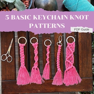 Może przedstawiać: Pięć wzorów różowych breloków z makramą z srebrnymi kółkami do kluczy. Breloki wiszą na drewnianej powierzchni. Tekst "5 BASIC KEYCHAIN KNOT PATTERNS" znajduje się w górnej części obrazu. Tekst "PDF Guide" znajduje się w prawym górnym rogu obrazu.