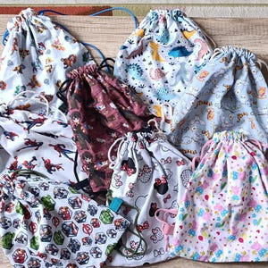 Peut inclure: Plusieurs sacs à cordon de serrage avec divers motifs, notamment des dinosaures, des super-héros et des personnages de dessins animés. Les sacs en tissu ont des cordons de serrage de différentes couleurs. Les sacs sont de différentes tailles et conviennent au rangement ou aux voyages.