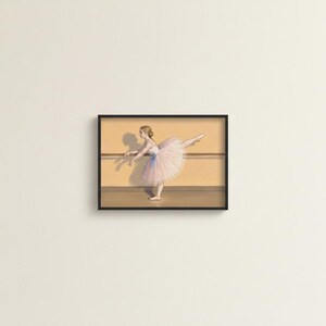 May include: A framed print of a ballerina in a pink tutu, practicing at a ballet barre. The artwork features soft colors and a classic style, with the dancer in a graceful pose. The background is a warm, neutral tone.