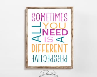 May include: A framed print with the text "Sometimes all you need is a different perspective" in colorful, vertical lettering. The text is in a variety of colors, including pink, orange, teal, and purple.
