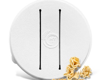 May include: White round pasta maker with two slots for making pasta. The pasta maker has a logo that says "MY" with a wheat stalk design. There are pieces of fresh pasta in the foreground.
