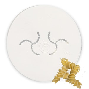 May include: White plastic pasta maker with a circular shape and a design of three spirals. The maker is shown with a sample of the pasta it creates, which is a yellow, twisted, spiral-shaped pasta.
