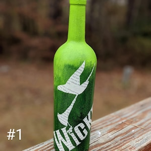 Puede incluir: Una botella de vidrio verde con un tap&oacute;n de corcho. La botella est&aacute; decorada con una silueta blanca de un p&aacute;jaro y la palabra "Wick" en letras blancas. La botella est&aacute; sobre una superficie de madera.