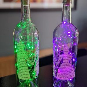 Puede incluir: Dos botellas de vidrio con tapas de corcho, llenas de luces de hadas coloridas. Las botellas est&aacute;n decoradas con etiquetas de papel impresas y tienen un aspecto vintage.