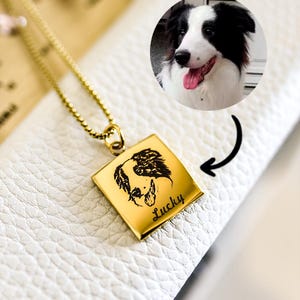以下が含まれることがあります： 黒と白の犬の肖像画と「ラッキー」という名前が刻まれた正方形のペンダントが付いたゴールドネックレスです。