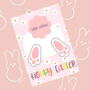 Könnte beinhalten: Eine rosa Karte mit einer weißen Hasenkontur und dem Text "Hoppy Easter" in Regenbogenfarben. Der Hase hat rosa Füße und einen weißen Schwanz. Die Karte ist mit weißen Gänseblümchen und dem Text "with cookie" in einem rosa Kreis verziert.