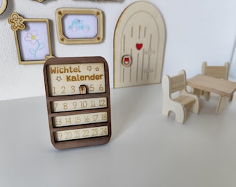 May include: Wooden advent calendar with the text "Wichtel Kalender" and numbers 1-24. The calendar is brown with a light-colored background. Also pictured are miniature wooden frames, a door, and furniture.