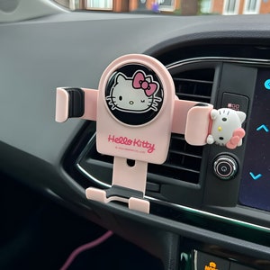 May include: Pink Hello Kitty car phone holder with a black and white Hello Kitty image and the text "Hello Kitty" and "©1976 SANRIO CO., LTD.".
