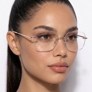 May include: Rimless eyeglasses featuring thin, metallic rose gold temples and a bridge. The lenses are clear, square-shaped with rounded corners, and are held in place by small metal hardware at the outer edges and the central bridge.