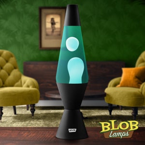 May include: A black lava lamp with teal liquid and white blobs. The lamp has a black base and top, with the brand name "BLOB" on the base. The background includes green walls, two yellow armchairs, and a wooden cabinet.