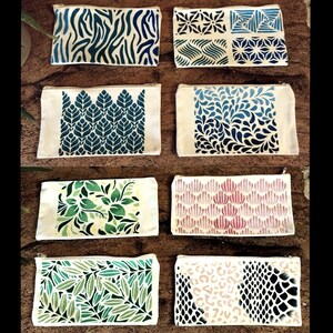 Op de afbeelding: Tien verschillende stoffen tasjes met verschillende geometrische en bloemmotieven. De tasjes zijn allemaal wit met verschillende gekleurde ontwerpen. De ontwerpen omvatten een zebrapatroon, een bloemenpatroon, een geometrisch patroon, een golfpatroon, een bladpatroon, een schelpvormig patroon, een luipaardpatroon en een slangenhuidpatroon.
